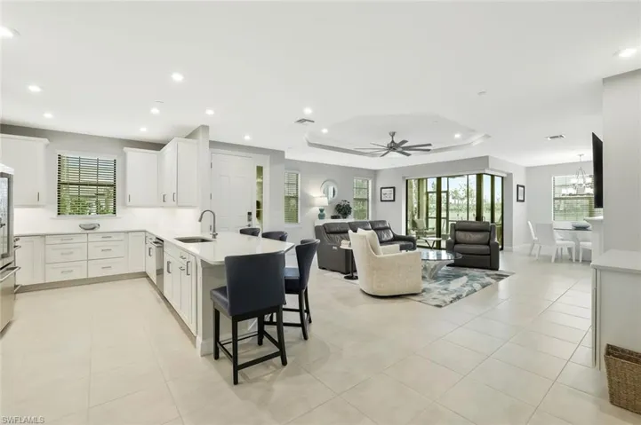 Kitchen featuring white cabinets, a peninsula, a kitchen breakfast bar, open floor plan, and a tray ceiling