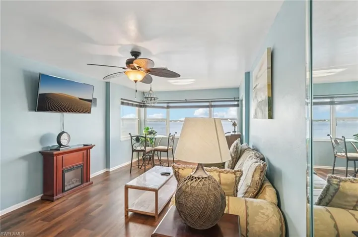 Living room featuring wood finished floors, ceiling fan, and a glass covered fireplace