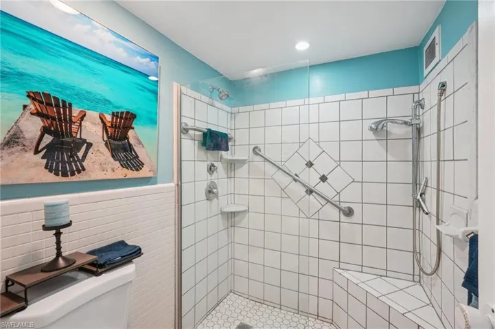 Full bath with a stall shower, a wainscoted wall, and tile walls