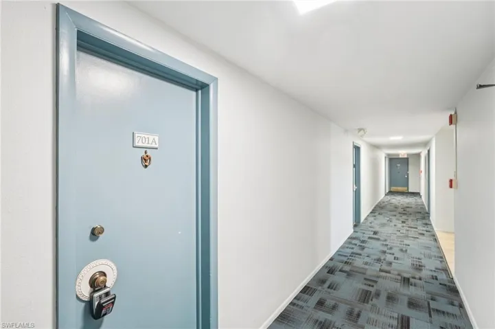 Hallway with carpet flooring and baseboards