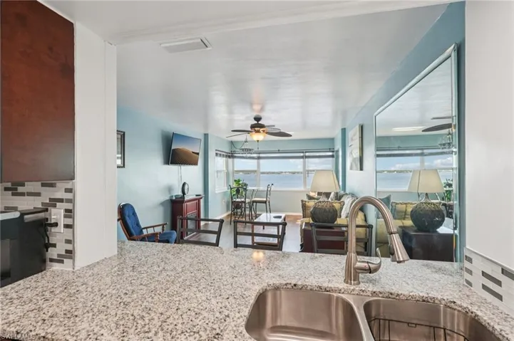 Kitchen with decorative backsplash, light stone counters, and a ceiling fan