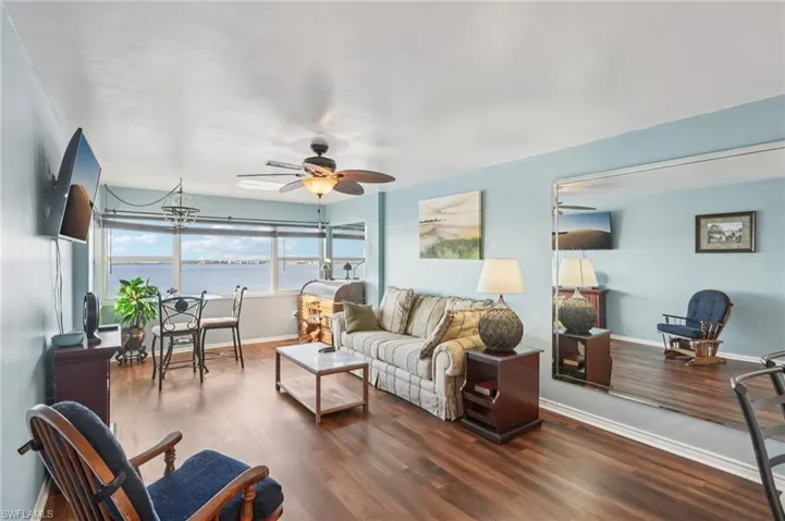 Living room with a ceiling fan, dark wood-style floors, and a chandelier