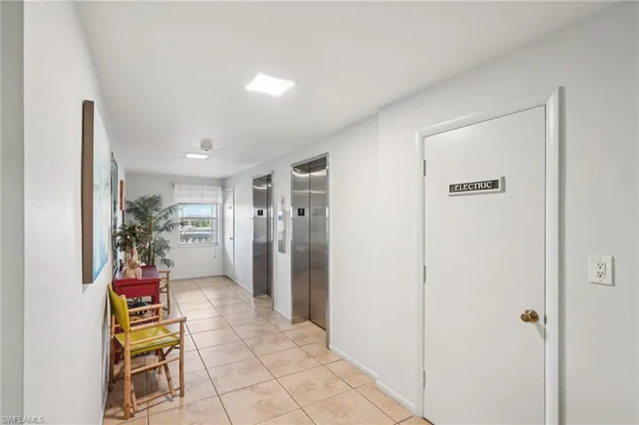 Hallway with light tile patterned floors and elevator