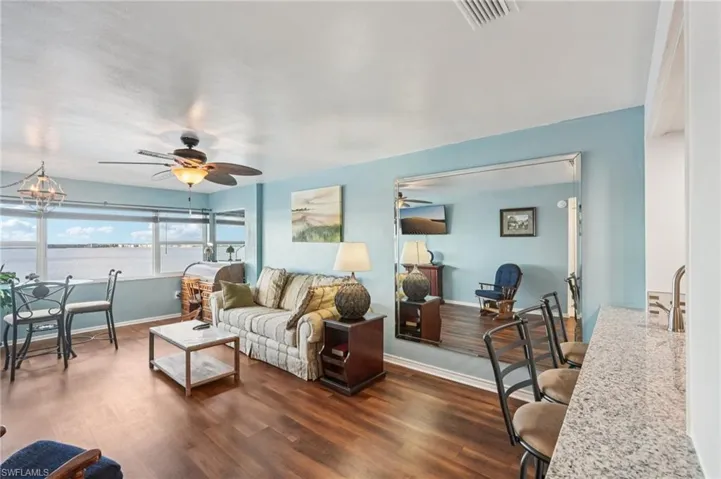 Living room featuring dark wood-style flooring, a ceiling fan, and a water view
