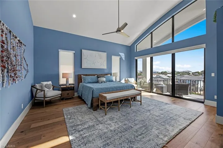 Bedroom featuring high vaulted ceiling, ceiling fan, wood flooring, and access to outside