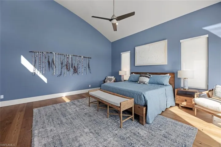 Bedroom with high vaulted ceiling, ceiling fan, and wood flooring
