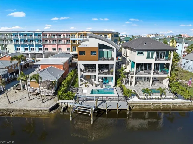 Rear view of house featuring a pool, a patio area, a balcony, and a water view