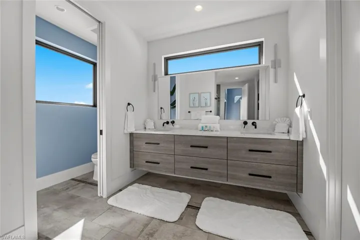 Bathroom featuring tile floors, dual vanity, and toilet