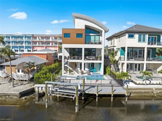 Rear view of house with a balcony, a swimming pool, a water view, and a patio
