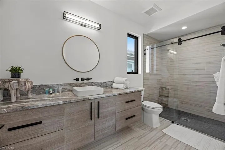 Bathroom with walk in shower, vanity, toilet, and tile floors