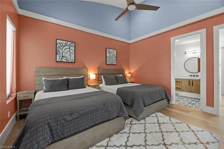 Bedroom featuring ensuite bathroom, ceiling fan, hardwood / wood flooring, sink, and a high ceiling