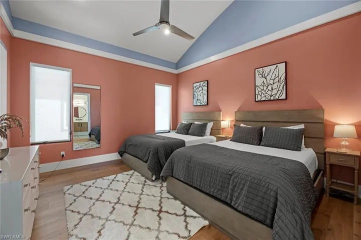 Bedroom featuring wood flooring, ceiling fan, and vaulted ceiling