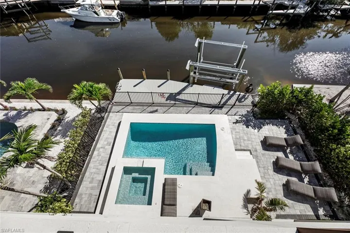 View of swimming pool with a boat dock, a water view, and a patio area