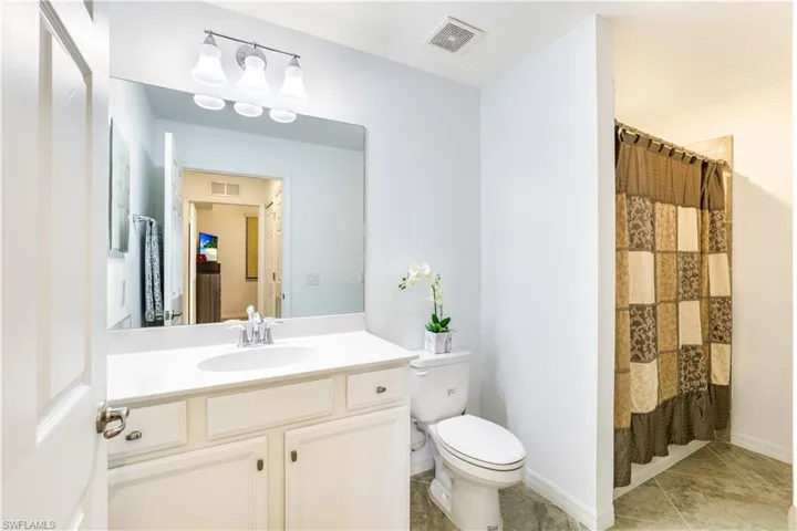 Bathroom with a shower with curtain, vanity, and light tile patterned flooring