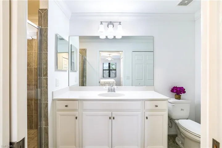 Ensuite bathroom with a stall shower, vanity, and ornamental molding