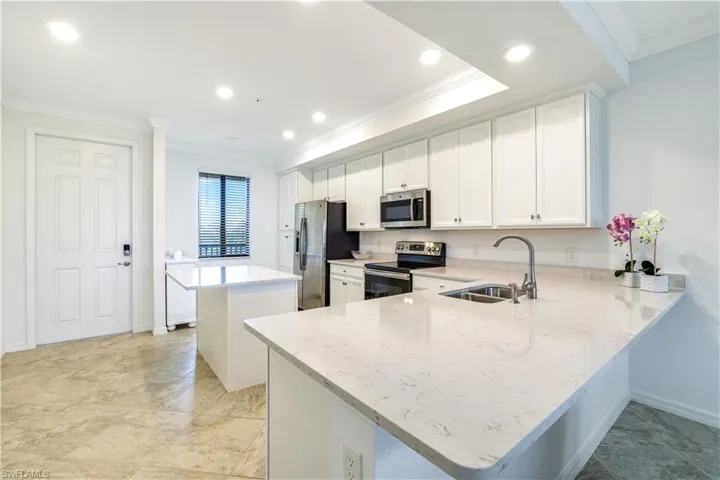 Kitchen with ornamental molding, white cabinetry, a center island, stainless steel appliances, and a kitchen breakfast bar