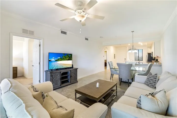 Living room featuring arched walkways, ornamental molding, ceiling fan, and suspended lighting