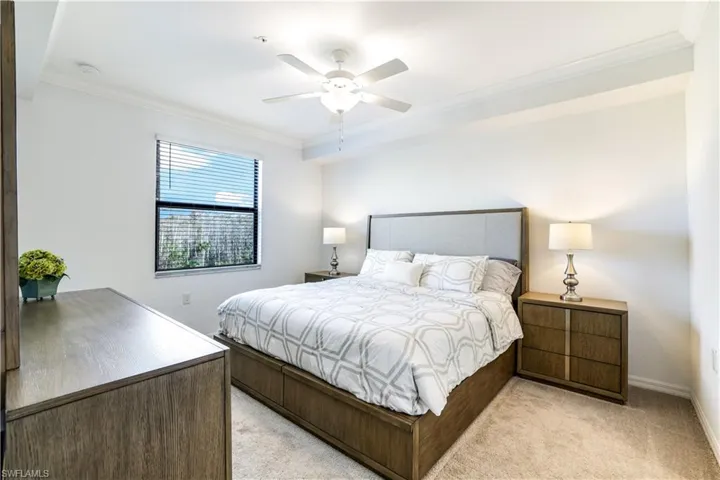 Bedroom featuring ornamental molding, light colored carpet, and a ceiling fan