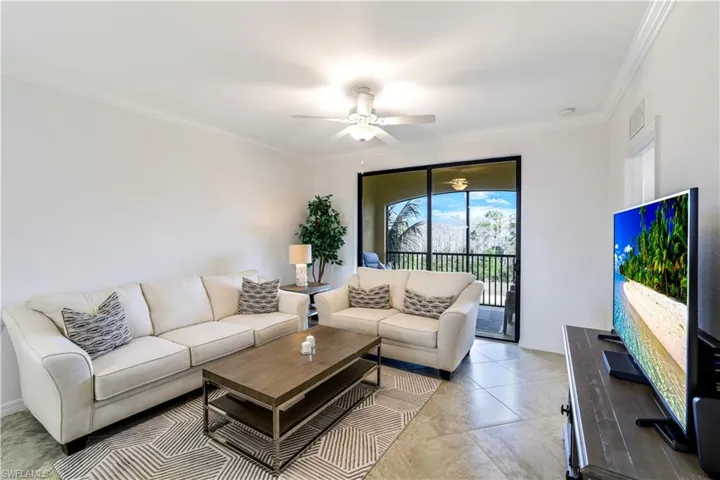Tiled living room with ornamental molding and ceiling fan