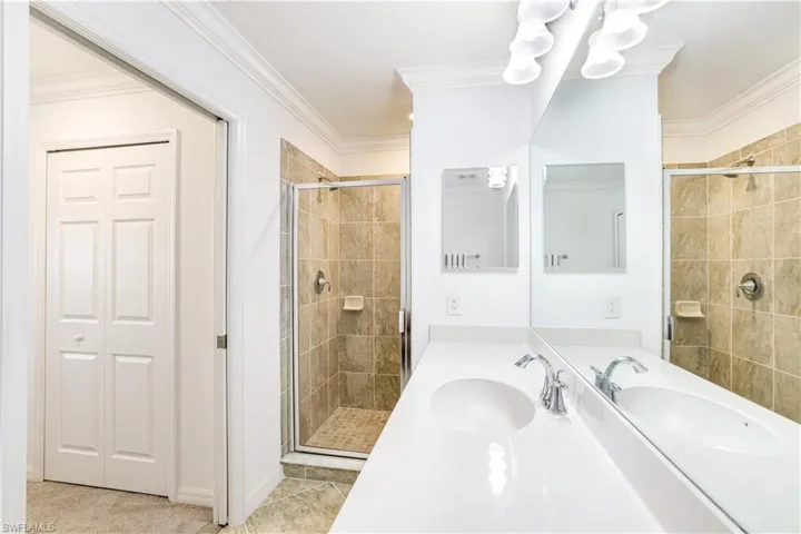 Full bathroom featuring a stall shower, vanity, and crown molding