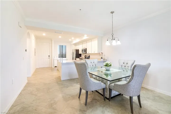 Dining space with ornamental molding, hanging lights, and arched walkways