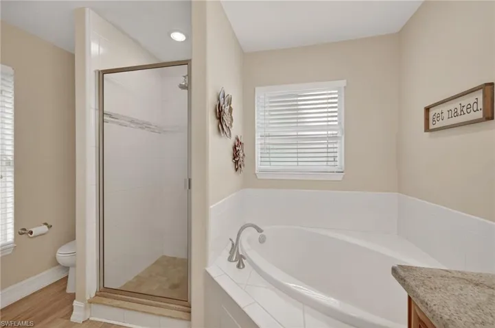 Full bath featuring a garden tub, a stall shower, and healthy amount of natural light