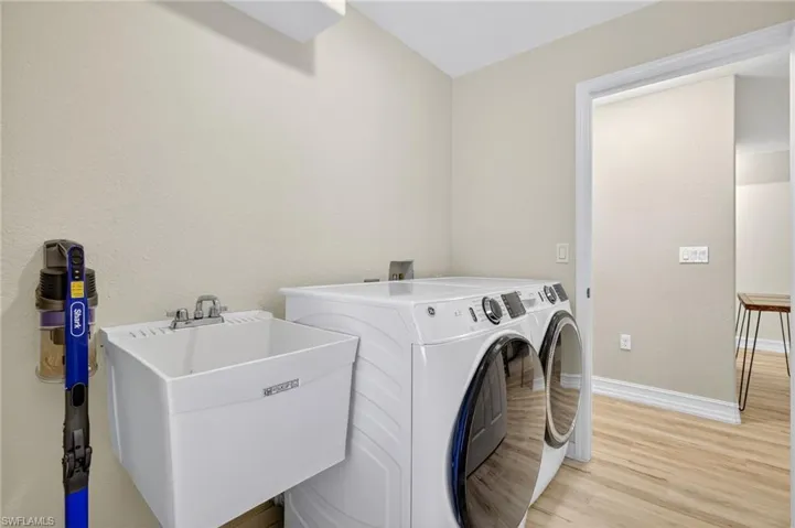Laundry area with washer and clothes dryer and light wood finished floors