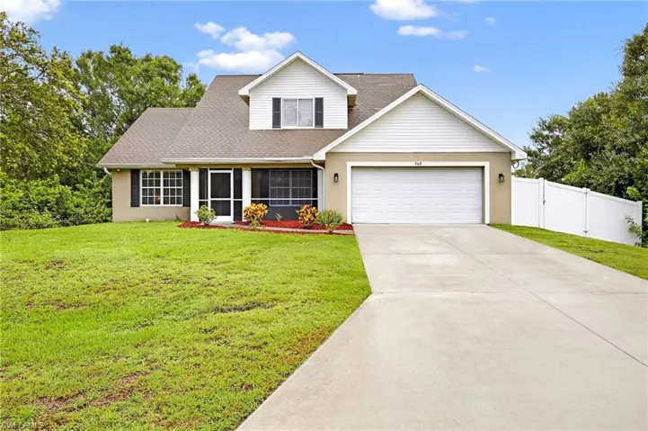 Traditional-style house featuring a garage, driveway, stucco siding, and a shingled roof