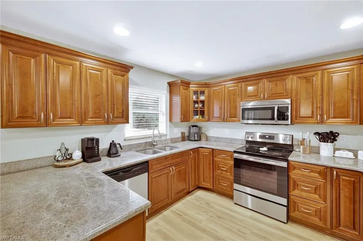 Kitchen with stainless steel appliances, brown cabinets, light wood finished floors, and recessed lighting