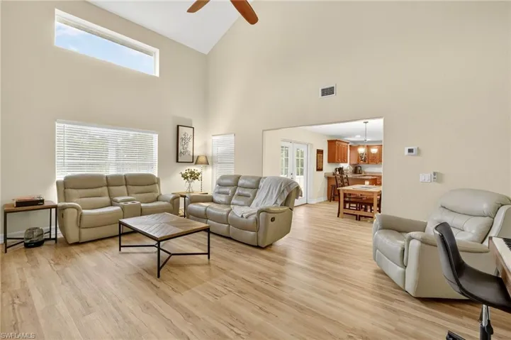 Living area with high vaulted ceiling, a ceiling fan, and light wood finished floors