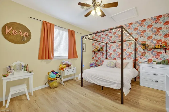 Bedroom featuring light wood-style flooring, attic access, and ceiling fan
