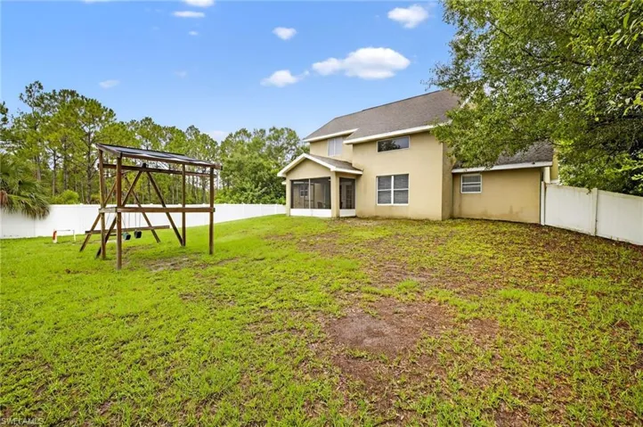 Back of house featuring a sunroom, a playground, a fenced backyard, and stucco siding