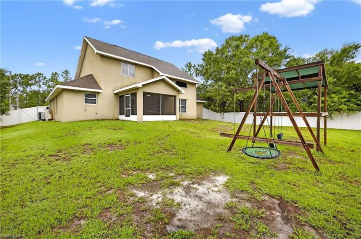 Back of house with a playground, a fenced backyard, a sunroom, stucco siding, and a shingled roof