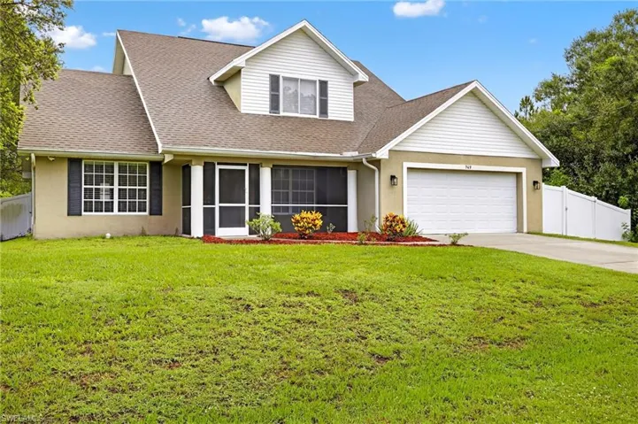 Traditional-style house with an attached garage, driveway, roof with shingles, and stucco siding
