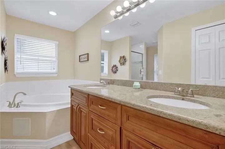 Full bath with double vanity, a garden tub, and a stall shower