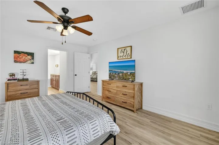 Bedroom featuring light wood finished floors, connected bathroom, and ceiling fan