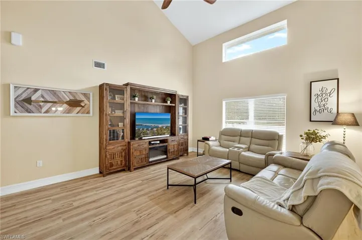 Living area featuring high vaulted ceiling, ceiling fan, and light wood-style flooring