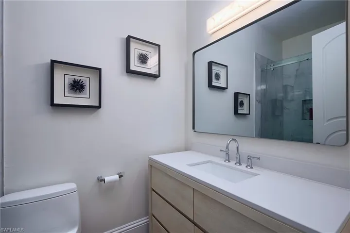 Modern bathroom featuring a single vanity with a light wood-finish cabinet, white countertop, and integrated rectangular sink with a chrome faucet