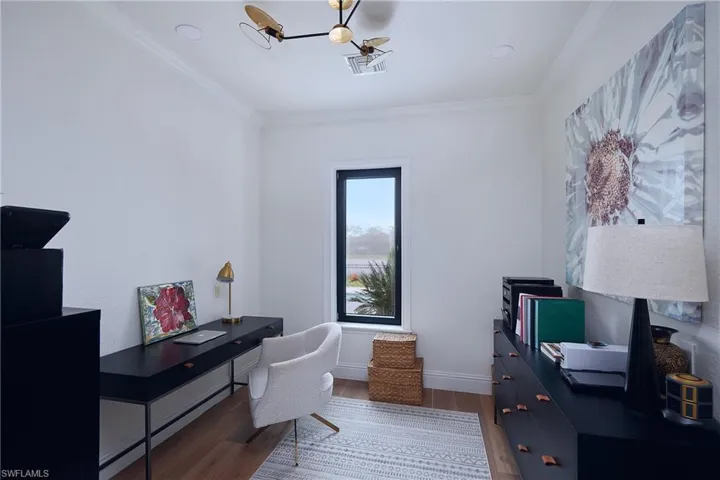 Interior room featuring a single vertical window with dark trim, crown molding, wood-finish flooring, a contemporary ceiling light fixture, and recessed lighting