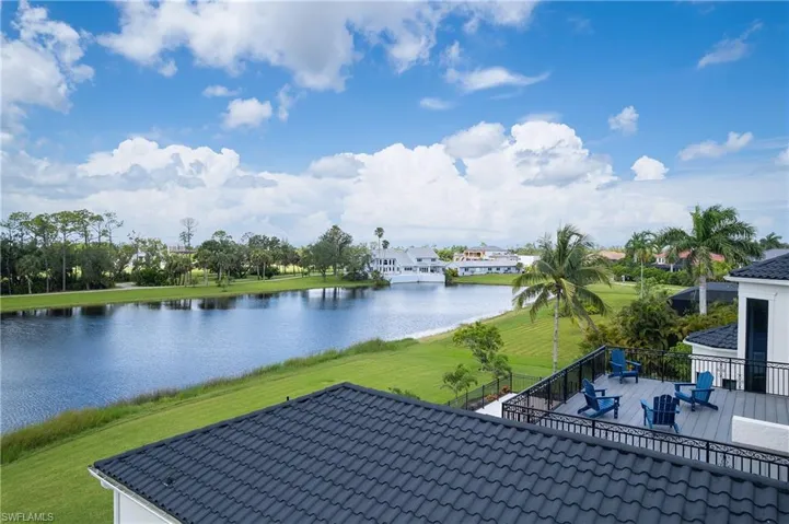 Expansive waterfront property featuring a large body of water, green grassy areas, and mature trees