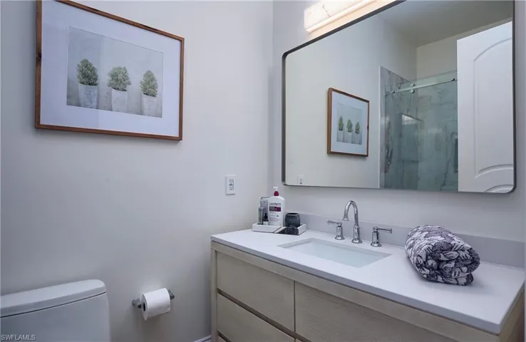 Bathroom featuring a oak wood-finish vanity with an integrated sink, polished chrome faucet, and a large framed mirror