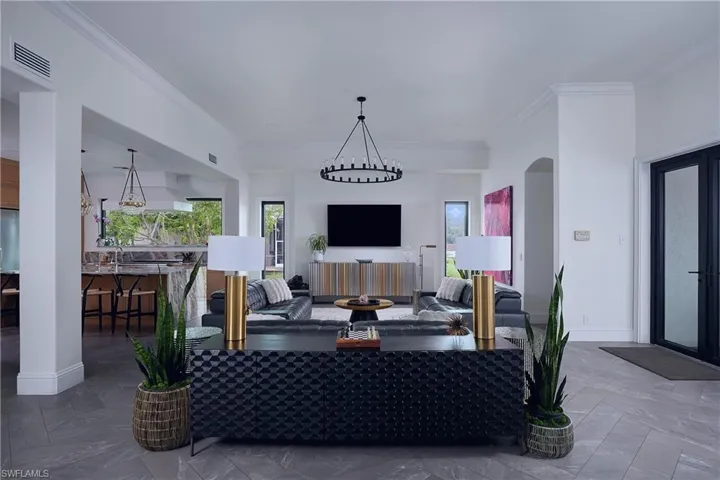 Spacious living area featuring herringbone-patterned tile flooring and high ceilings with crown molding