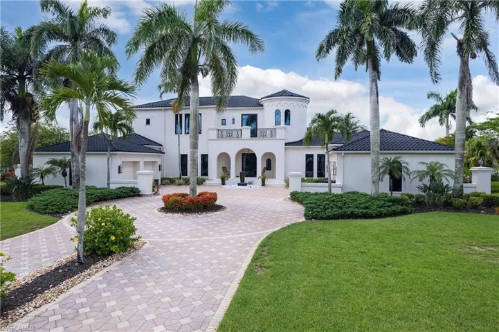 Grand residence featuring a white stucco exterior, black tile roof, and a prominent turret element