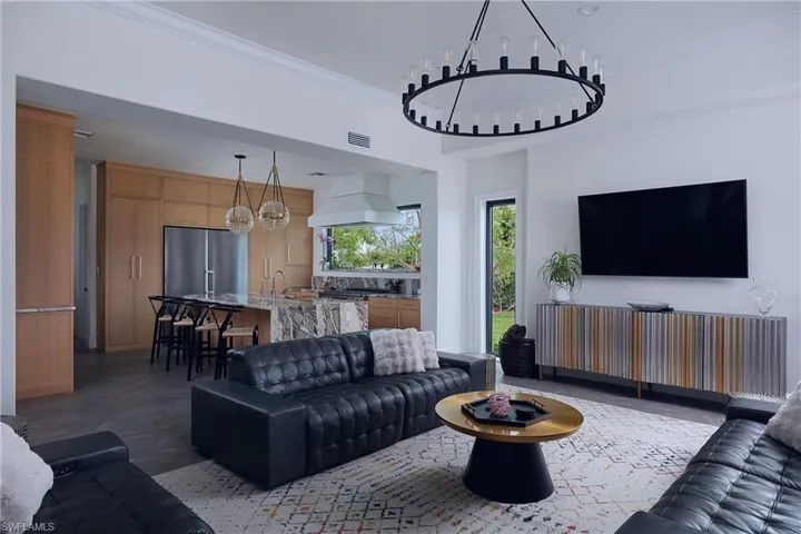 Open-concept living space featuring a large ceiling-mounted chandelier, recessed lighting, and light wood-finish cabinetry