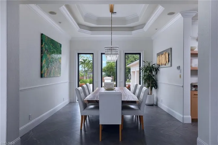 Formal dining space featuring dark tile flooring, wainscoting, and crown molding