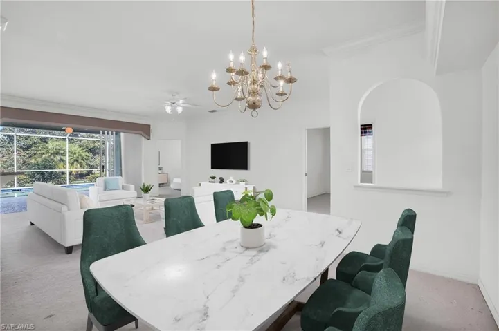 Dining area featuring light carpet, ceiling fan with notable chandelier, and ornamental molding