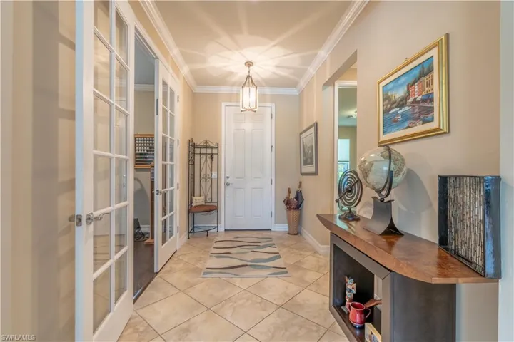 Entryway with french doors, light tile patterned floors, and ornamental molding