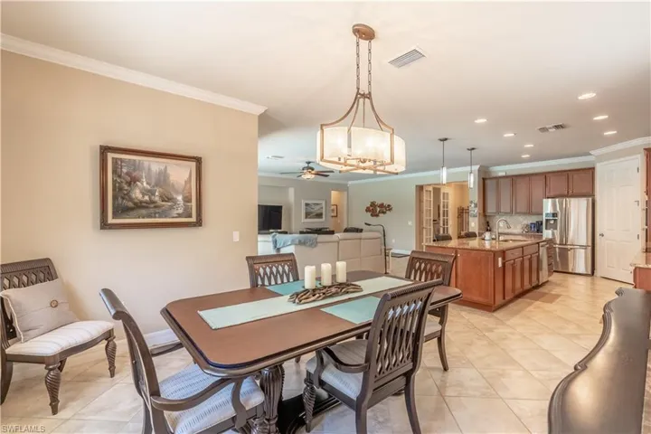 Dining room with light tile patterned floors, ceiling fan with notable chandelier, crown molding, and sink