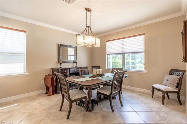 Dining space featuring light tile patterned flooring, a chandelier, and ornamental molding