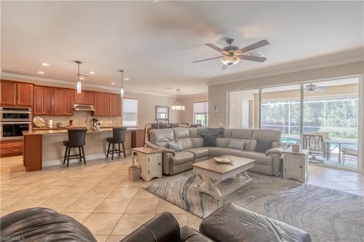 Living room featuring light tile patterned flooring, sink, crown molding, and ceiling fan